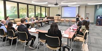 Professionals sitting at desks in a conference room while someone presents